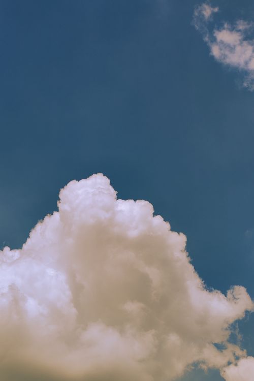 Free Bright fluffy clouds set against a vibrant blue sky evoke a sense of peace and tranquility. Stock Photo