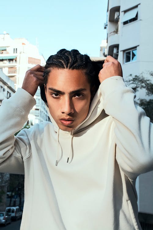 Young Man with Braided Hair Wearing a White Hoodie