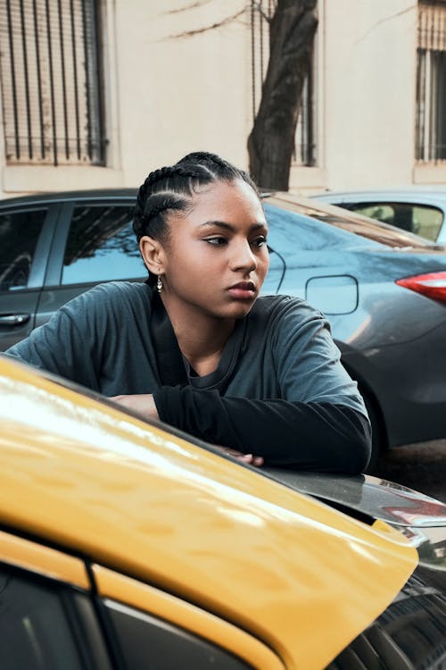 Model with Braided Hair Leaning Against a Yellow Car