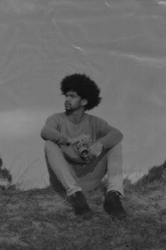 Black and white image of a man sitting outdoors with a camera in São Paulo, Brazil.