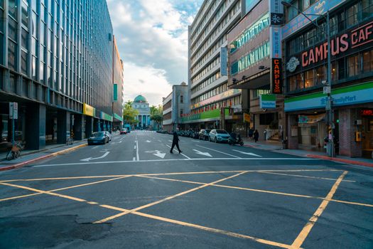 A bustling urban street scene featuring city buildings and pedestrians crossing.