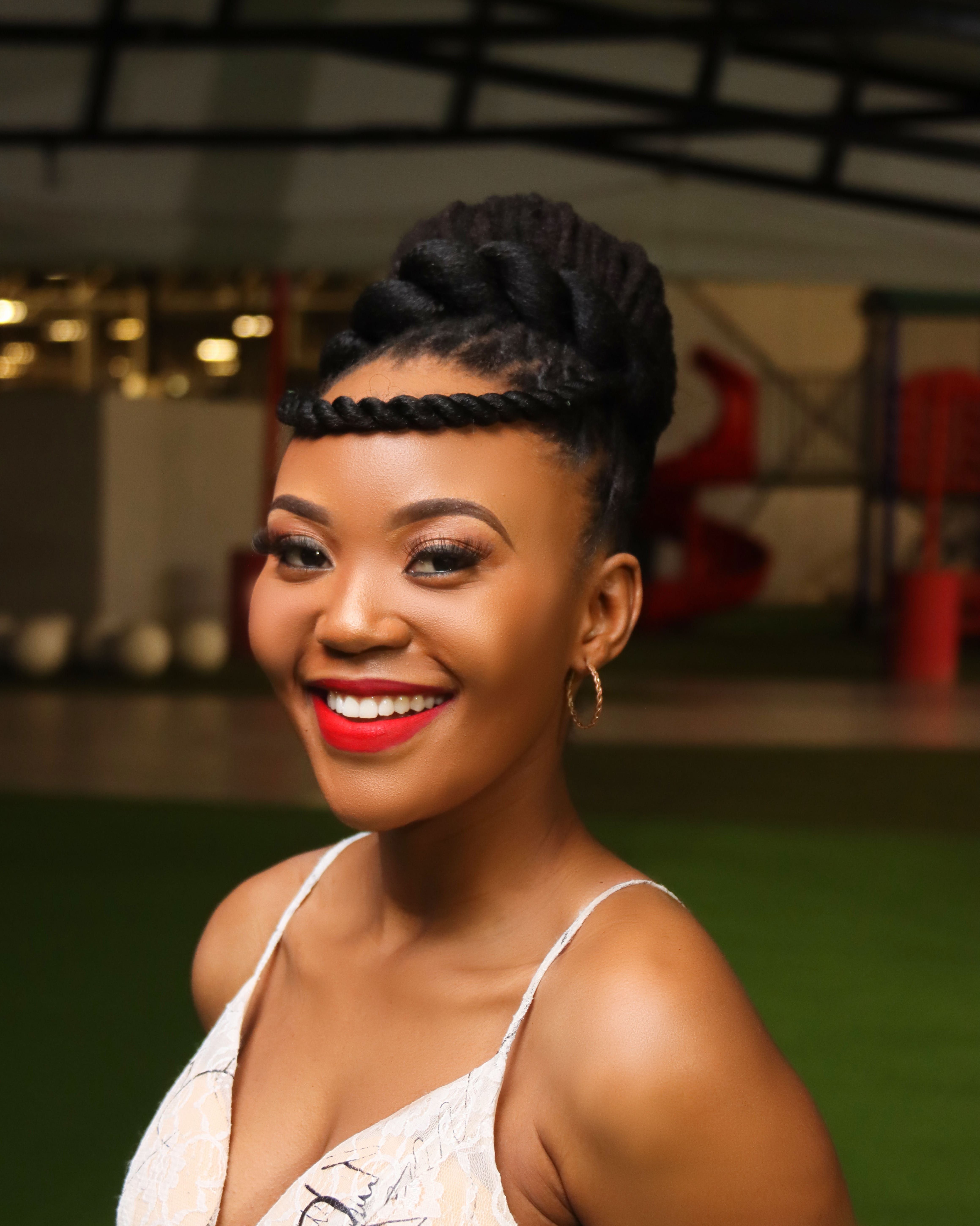 Charming portrait of a smiling African woman with braided hair and elegant attire.