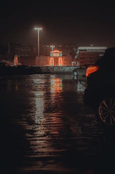 Rain-soaked cityscape with neon reflections in Stockport, England at night.