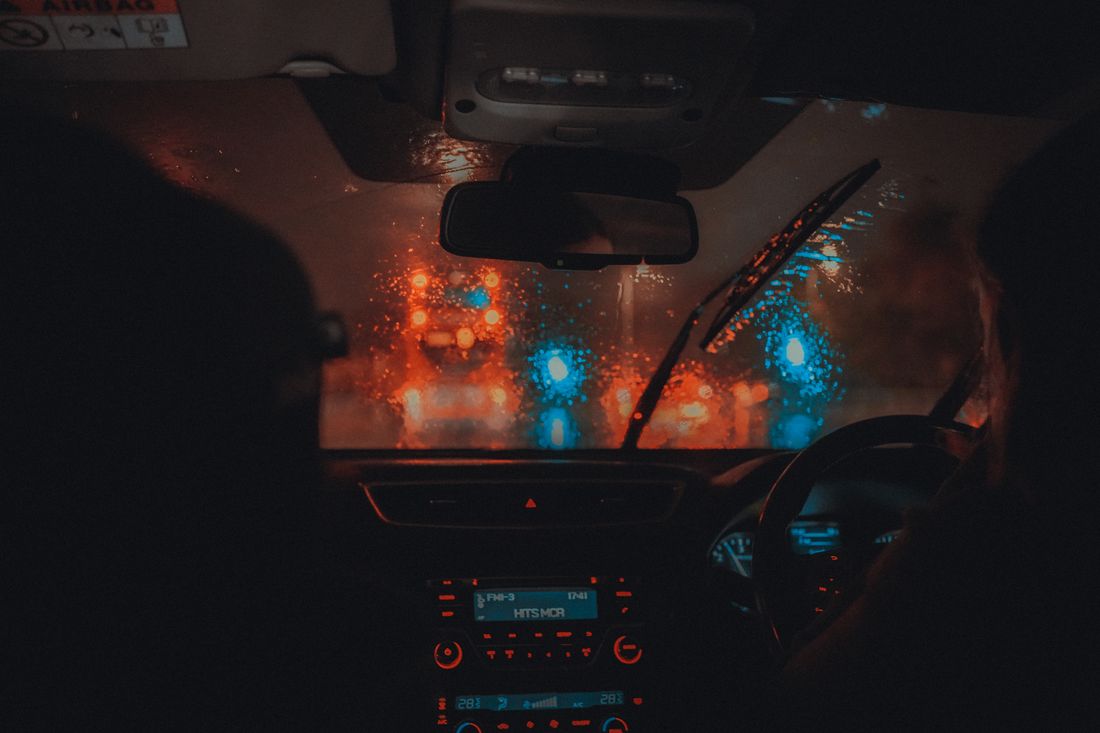 Cinematic view from car interior driving through Manchester at night in rain