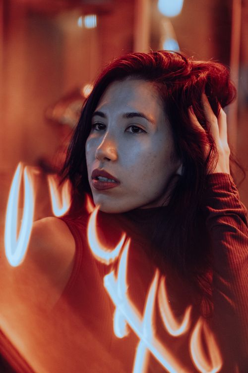 Free A dramatic portrait of a woman with neon reflections and a moody atmosphere. Stock Photo