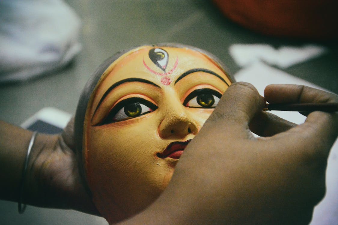 A close up view of a mask of Goddess Durga being hand-painted