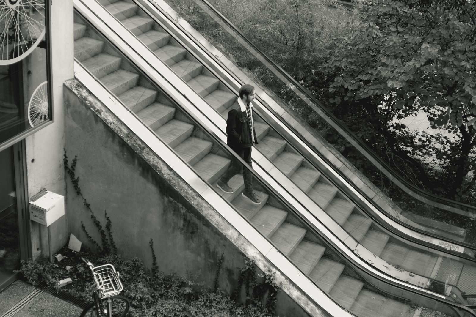 Homme en costume sur un escalator extérieur en noir et blanc
