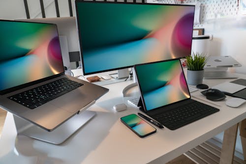 A Modern Desk with Laptops, a Monitor and Smartphone Displaying the Same Lockscreen 