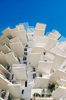 A striking view of L'Arbre Blanc in Montpellier, showcasing its unique balconies against a clear blue sky.