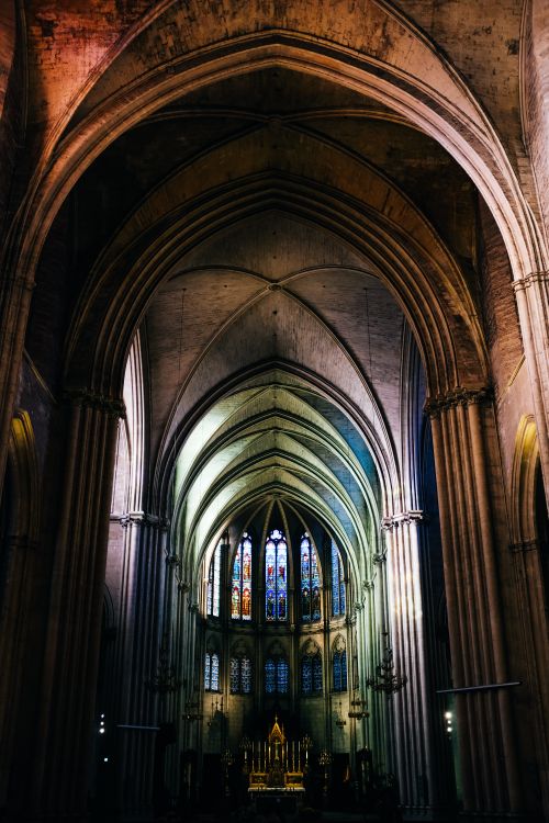 Free Stunning Gothic cathedral interior with high vaulted ceilings and vibrant stained glass windows. Stock Photo