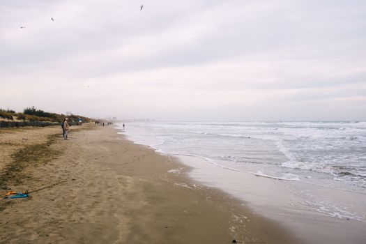 A tranquil beach scene with gentle waves and overcast skies, inviting a peaceful walk along the shore.