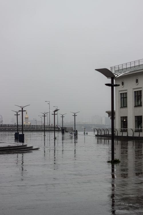 Free A gray, foggy day on a harbor promenade, showcasing modern street lights and architecture. Stock Photo