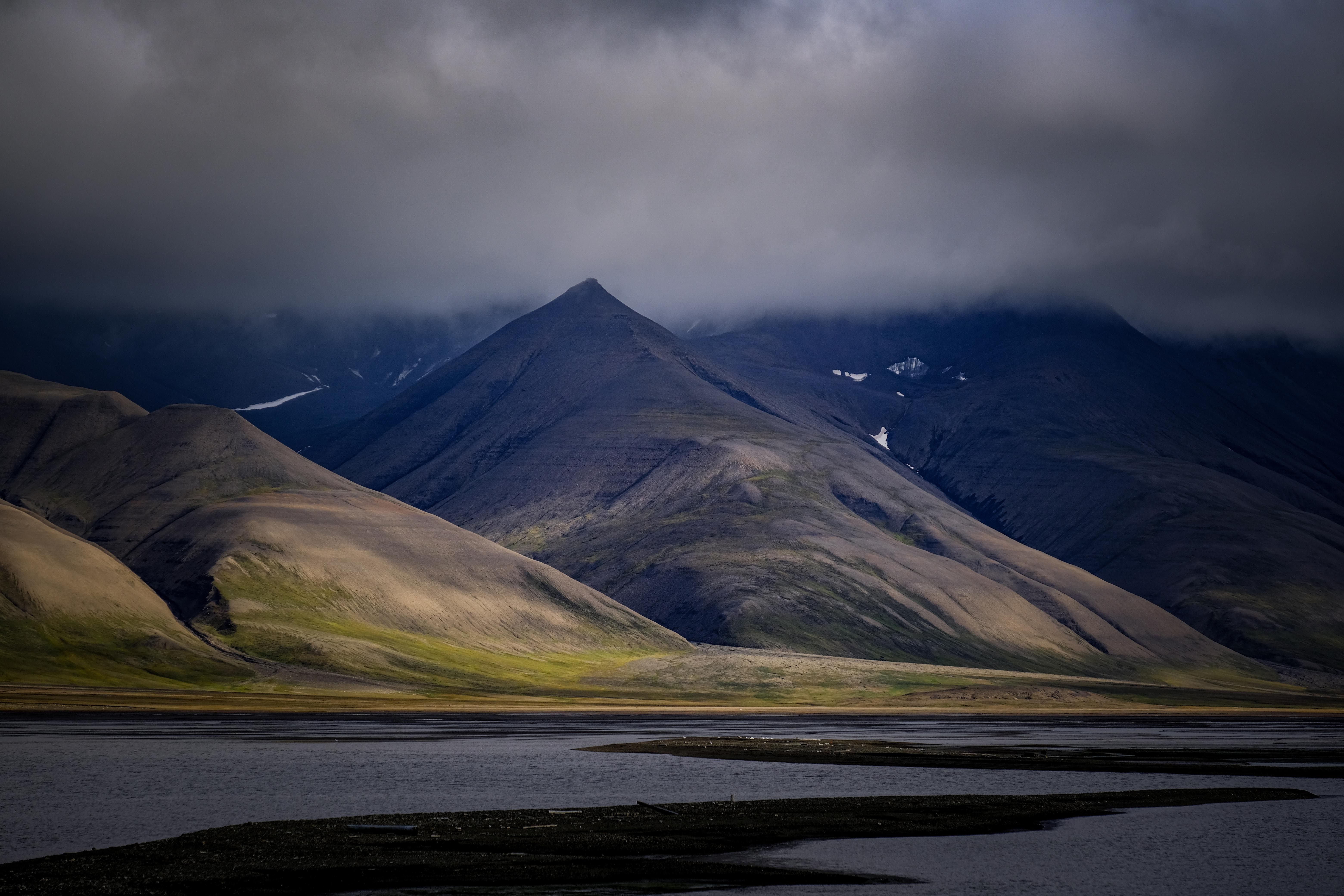 A striking view of rugged mountains beneath dark, moody clouds, reflecting tranquility and natural beauty.