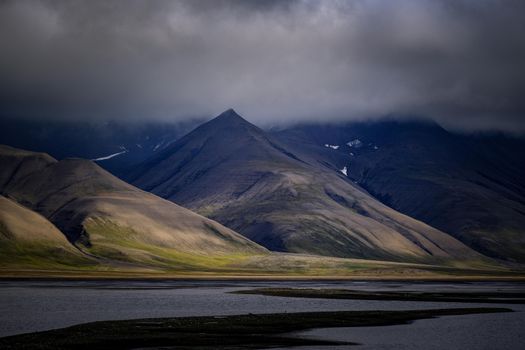 A striking view of rugged mountains beneath dark, moody clouds, reflecting tranquility and natural beauty.