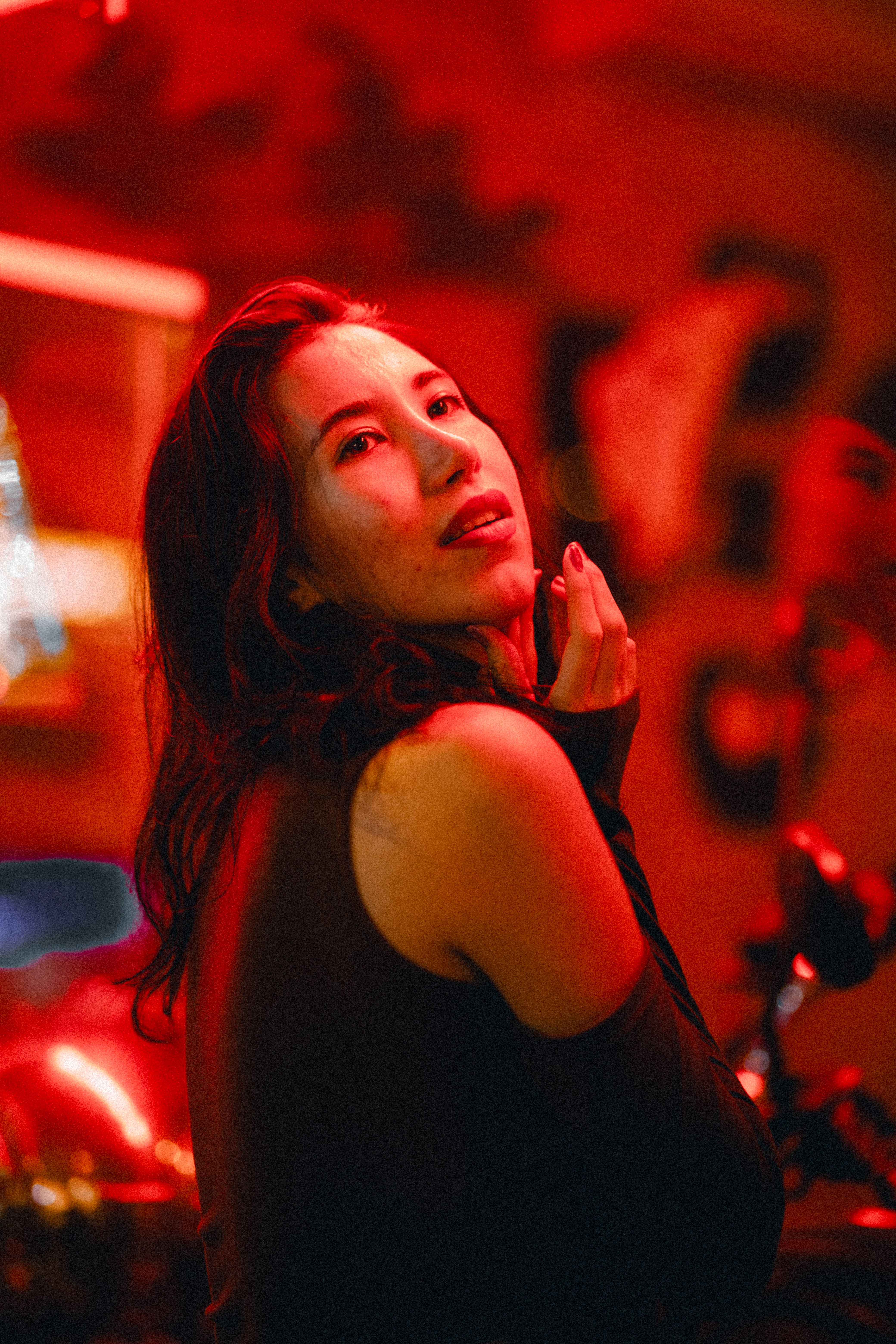 Elegant portrait of a woman in red lighting, showcasing beauty and mystery.