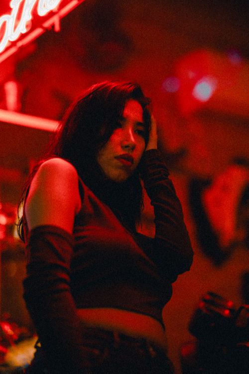 Free Artistic portrait of a woman under vibrant red lighting, showcasing a fashion-forward look. Stock Photo