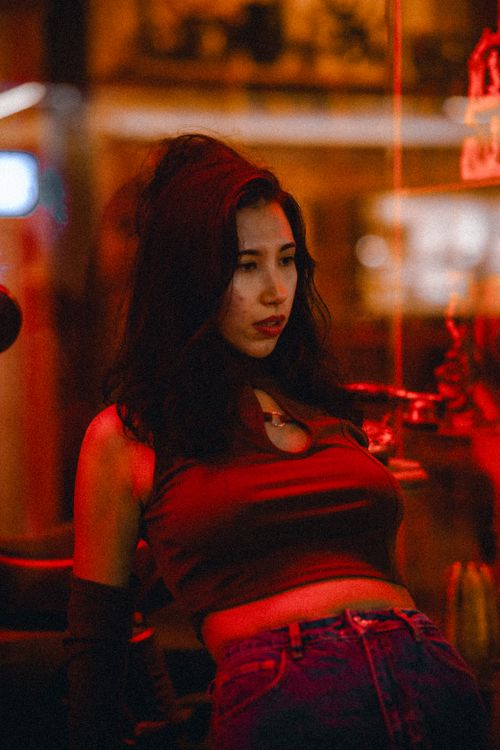 Free Artistic fashion portrait of a woman in red lighting, capturing modern urban style and mood. Stock Photo