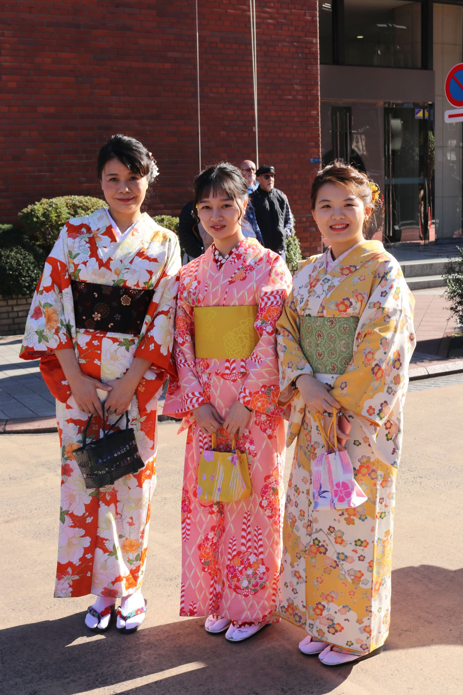 三位身穿彩色和服的女性走在日本传统街道上