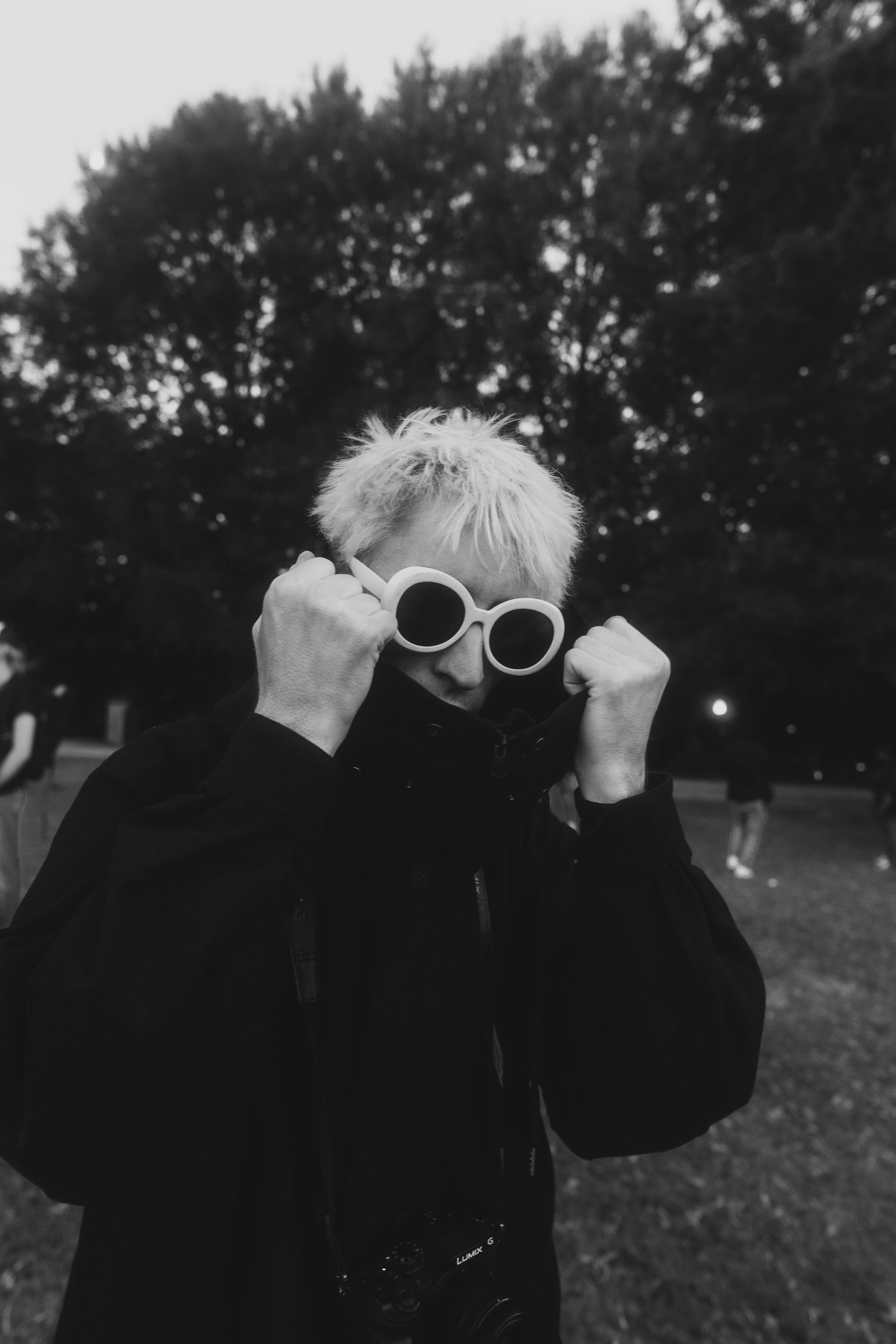 Black and white photo of a young man with sunglasses and jacket outside in an Atlanta park.