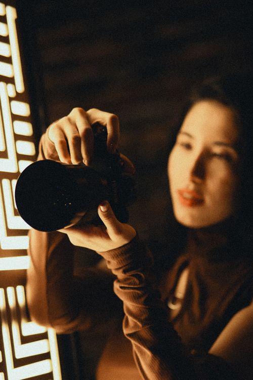 Free Stylish woman capturing a moment with DSLR camera in warm light. Stock Photo