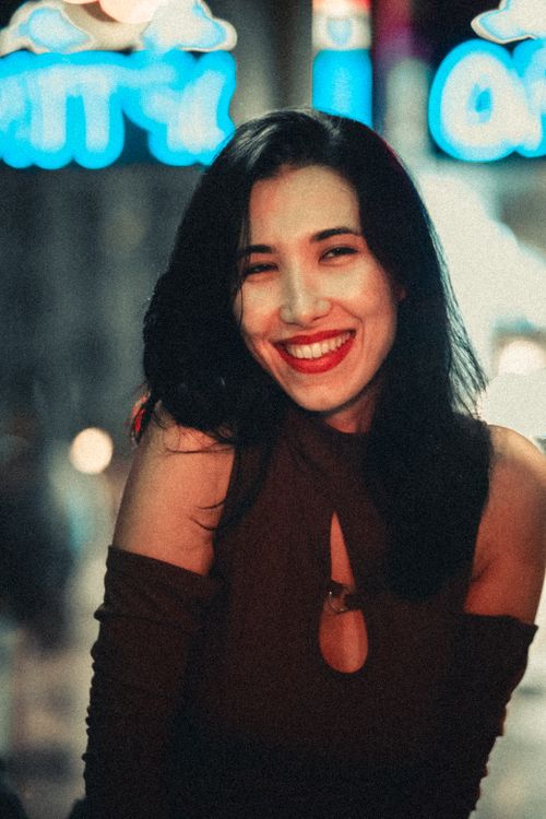 Free Portrait of a smiling young woman with red lipstick in urban night scene. Stock Photo
