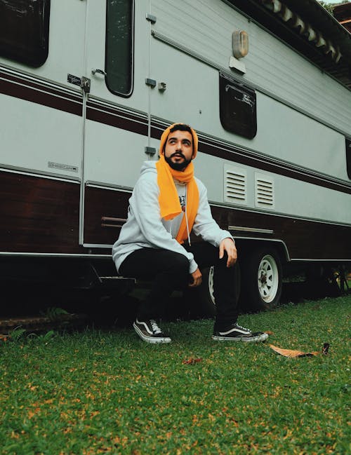 Man Sitting on White and Brown Recreational Vehicle
