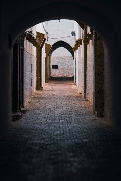 Free A moody cobblestone alley featuring gothic arches, typical of historic European towns. Stock Photo