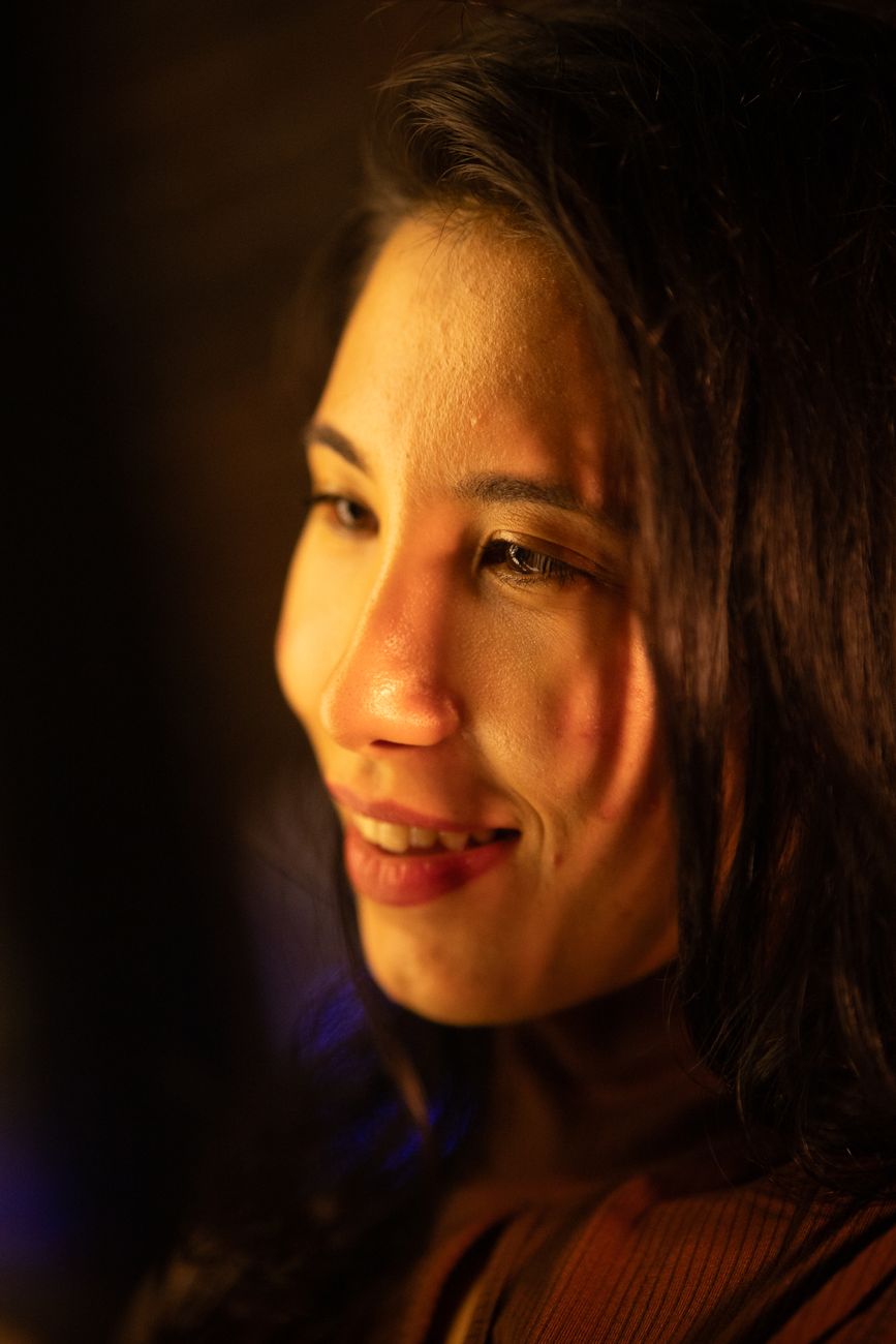 Close-up portrait of a smiling young woman in warm lighting.