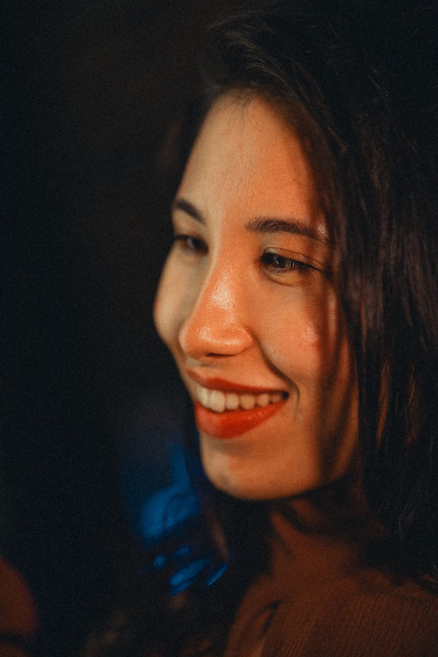 Close-up portrait of a smiling woman with warm lighting and engaging expression.