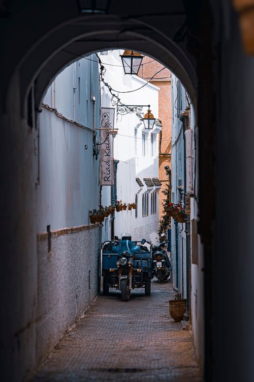 Free Charming narrow alleyway with vintage motorcycles under archway in historic urban area. Stock Photo