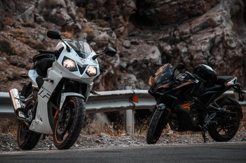 Free Two sport motorcycles parked by a rocky mountain road, perfect for adventure enthusiasts. Stock Photo