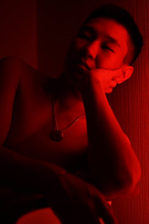 Bored Man Sitting With His Head on Hand in a Room with Red Light