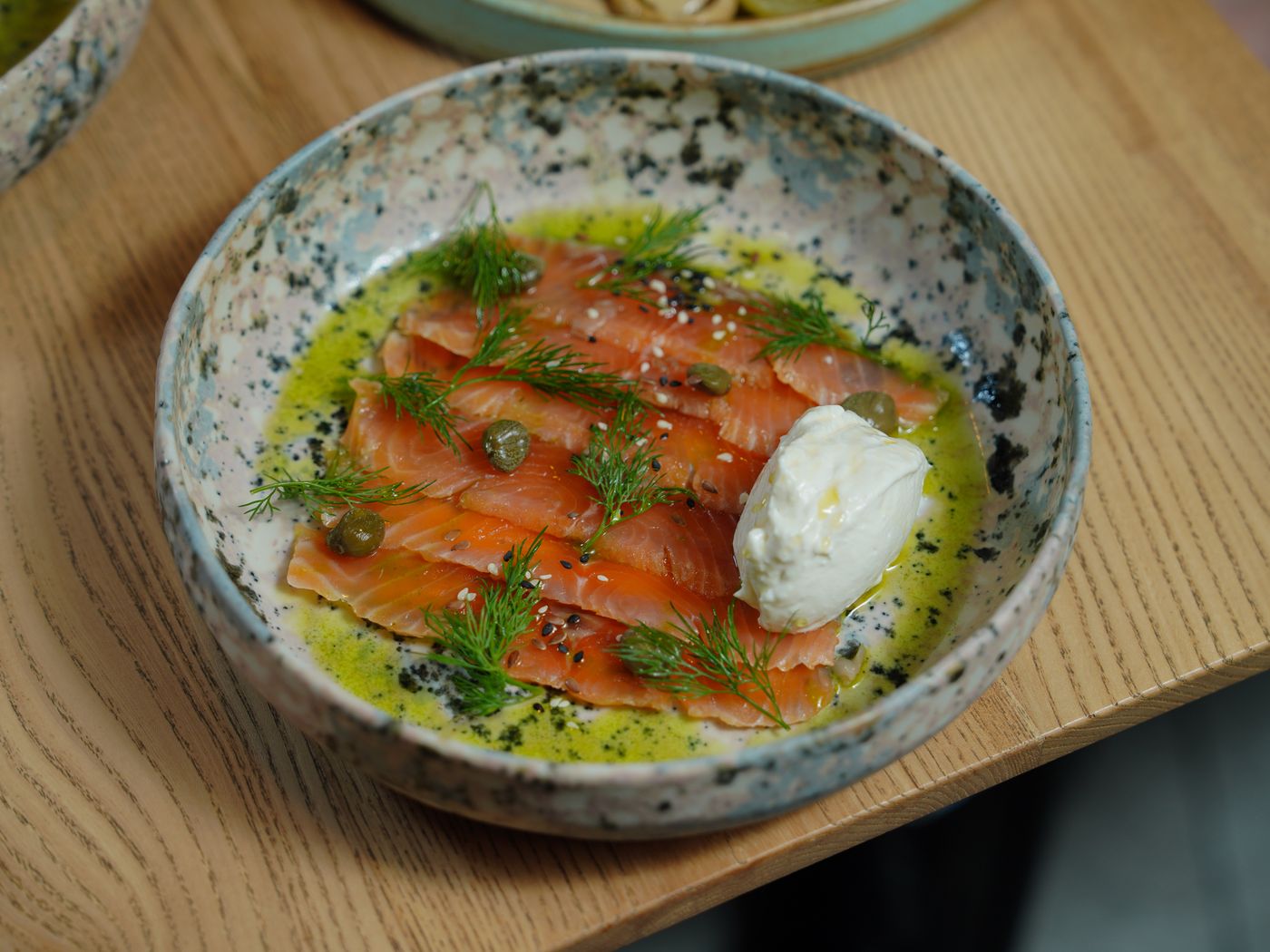 Appetizing smoked salmon with mozzarella cheese, dill, capers, and olive oil in a ceramic dish.