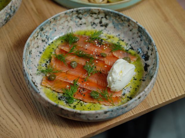Appetizing smoked salmon with mozzarella cheese, dill, capers, and olive oil in a ceramic dish.