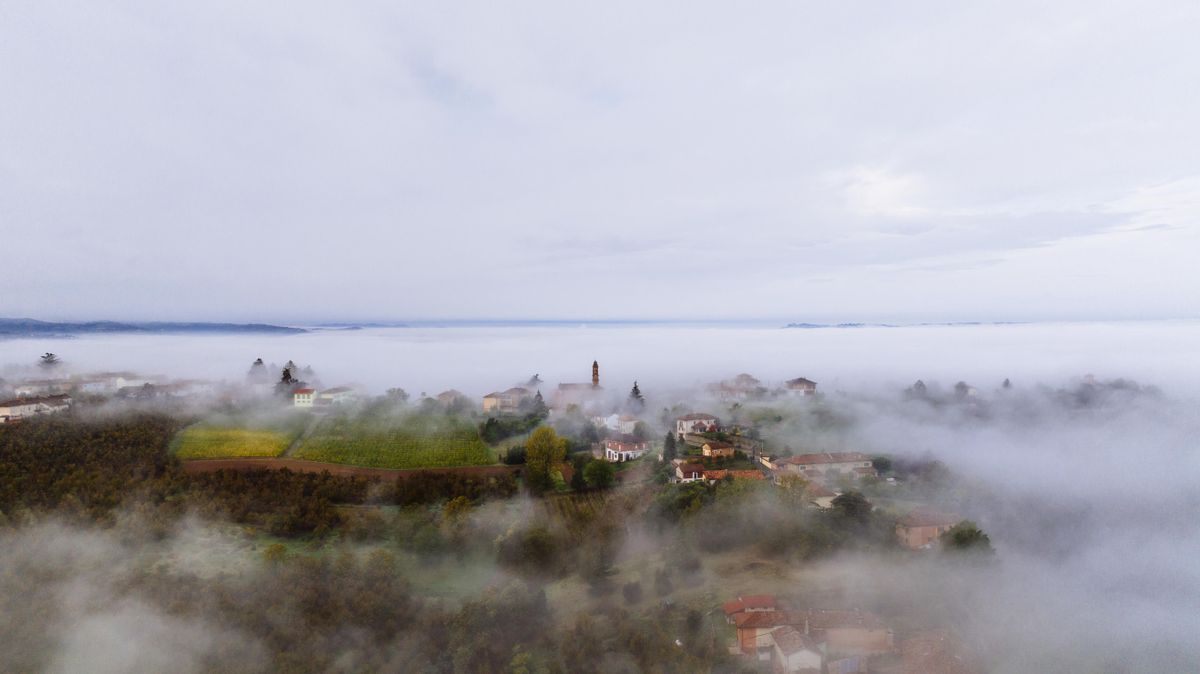 Dealuri si o clopotnita iesind dintr-o mare de ceata