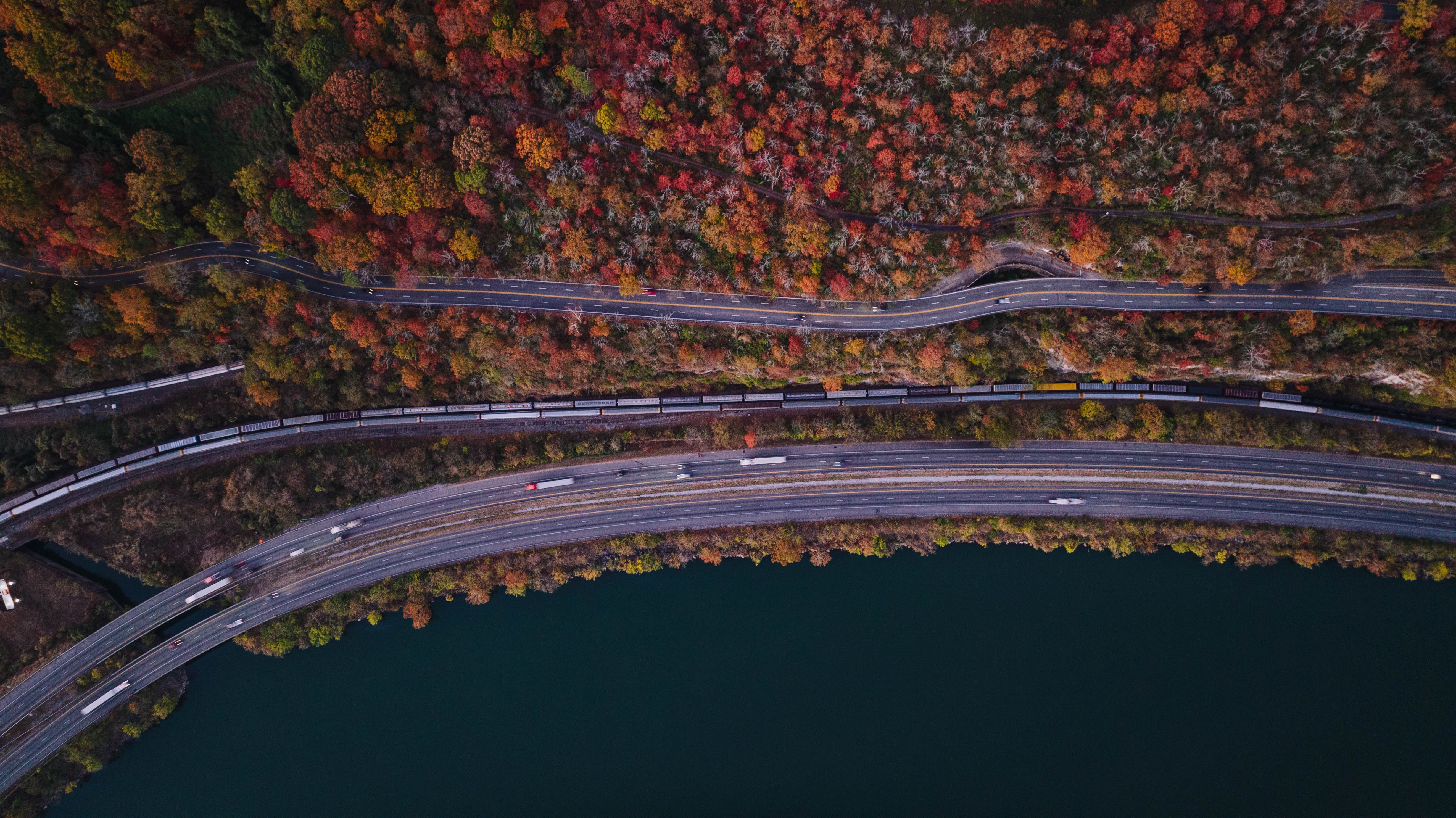 Aerial view showcasing vibrant fall foliage, roads, and a train track beside a river in Chattanooga, TN.