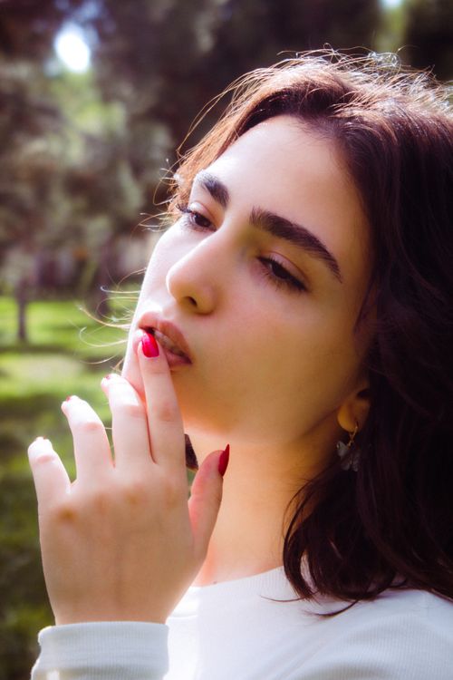 Free A close-up portrait of a young woman basking in the summer sunlight outdoors. Stock Photo