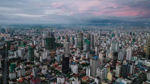 Free Dramatic aerial view of Phnom Penh's cityscape with high-rise buildings under a pink sky. Stock Photo
