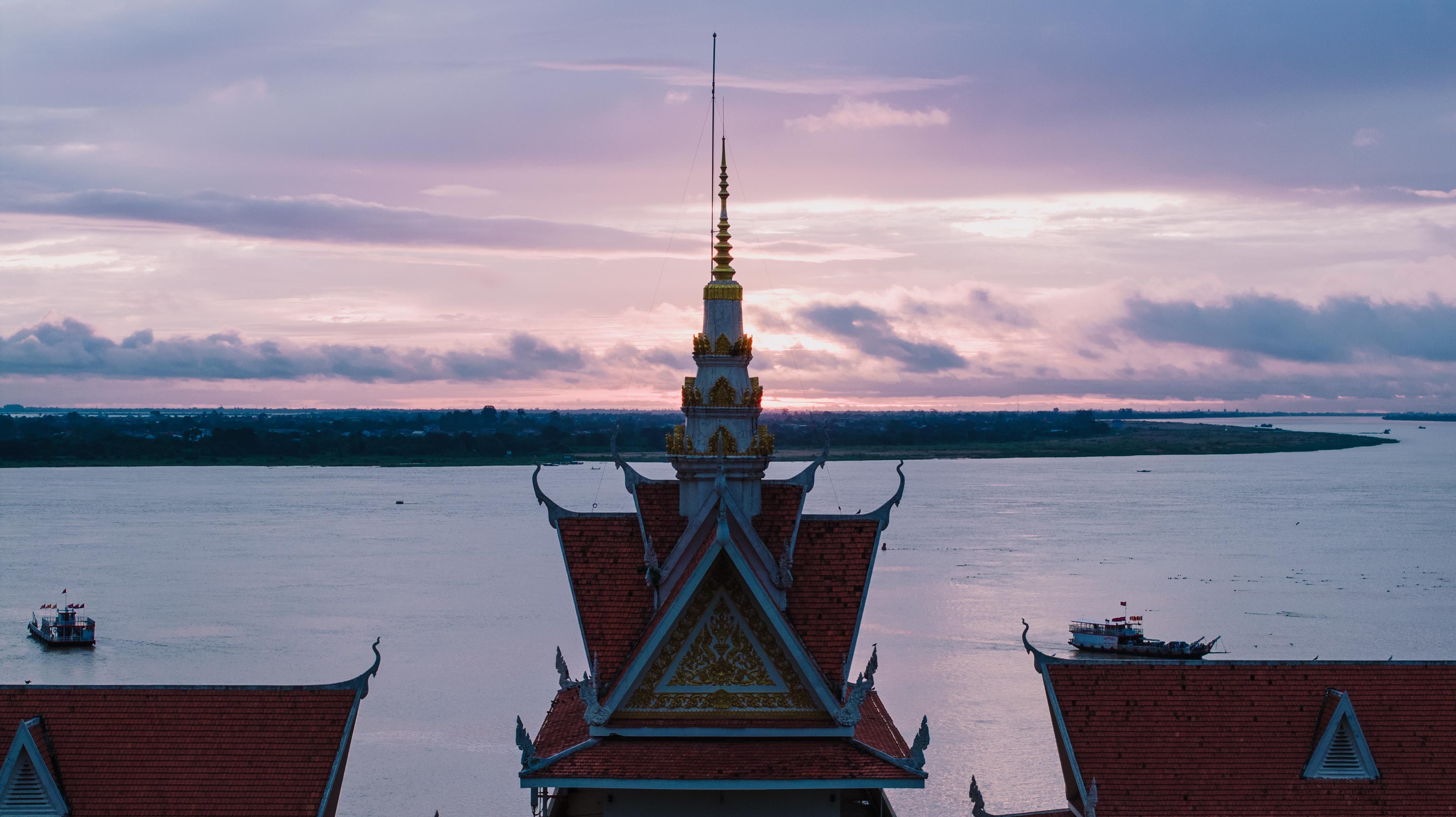 Aerial view of a Cambodian temple by the Mekong River during a beautiful sunset, capturing the serene and spiritual atmosphere.