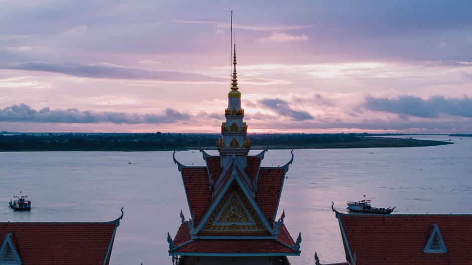 Aerial view of a Cambodian temple by the Mekong River during a beautiful sunset, capturing the serene and spiritual atmosphere.
