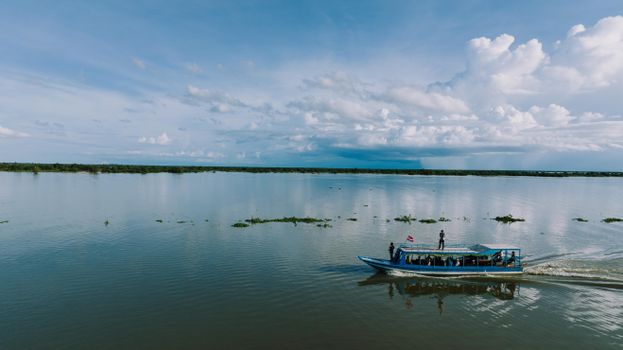 A serene view of a boat on Tonle Sap Lake under a vast sky in Cambodia.