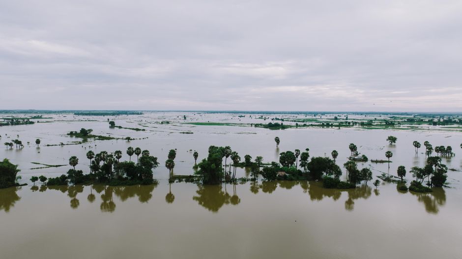 Photo by K Stunning aerial view of flooded landscape in Kampong Thom, Cambodia with palm trees and water reflections.