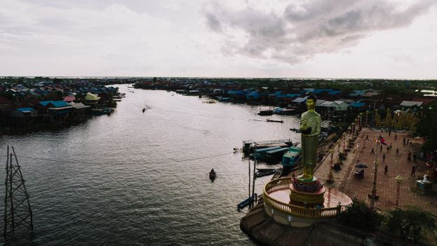 Aerial view of Kampong Khleang, Cambodia featuring a prominent Buddha statue by the riverside village.