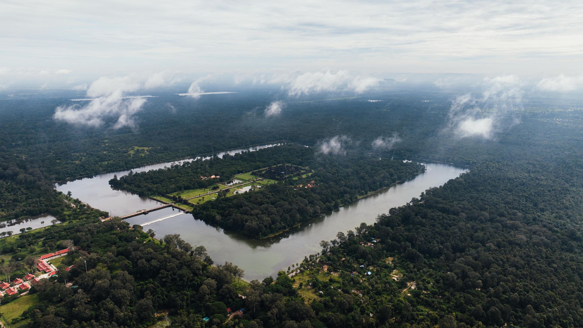 Stunning drone capture of Angkor Wat in Cambodia, enveloped in dense greenery and water.