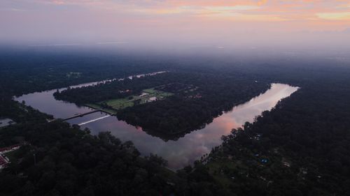 Free A breathtaking aerial view of Angkor Wat surrounded by lush forest at sunset, reflecting water bodies in Krong Siem Reap, Cambodia. Stock Photo