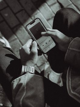 Man holding smartphone using music app, monochrome close-up.