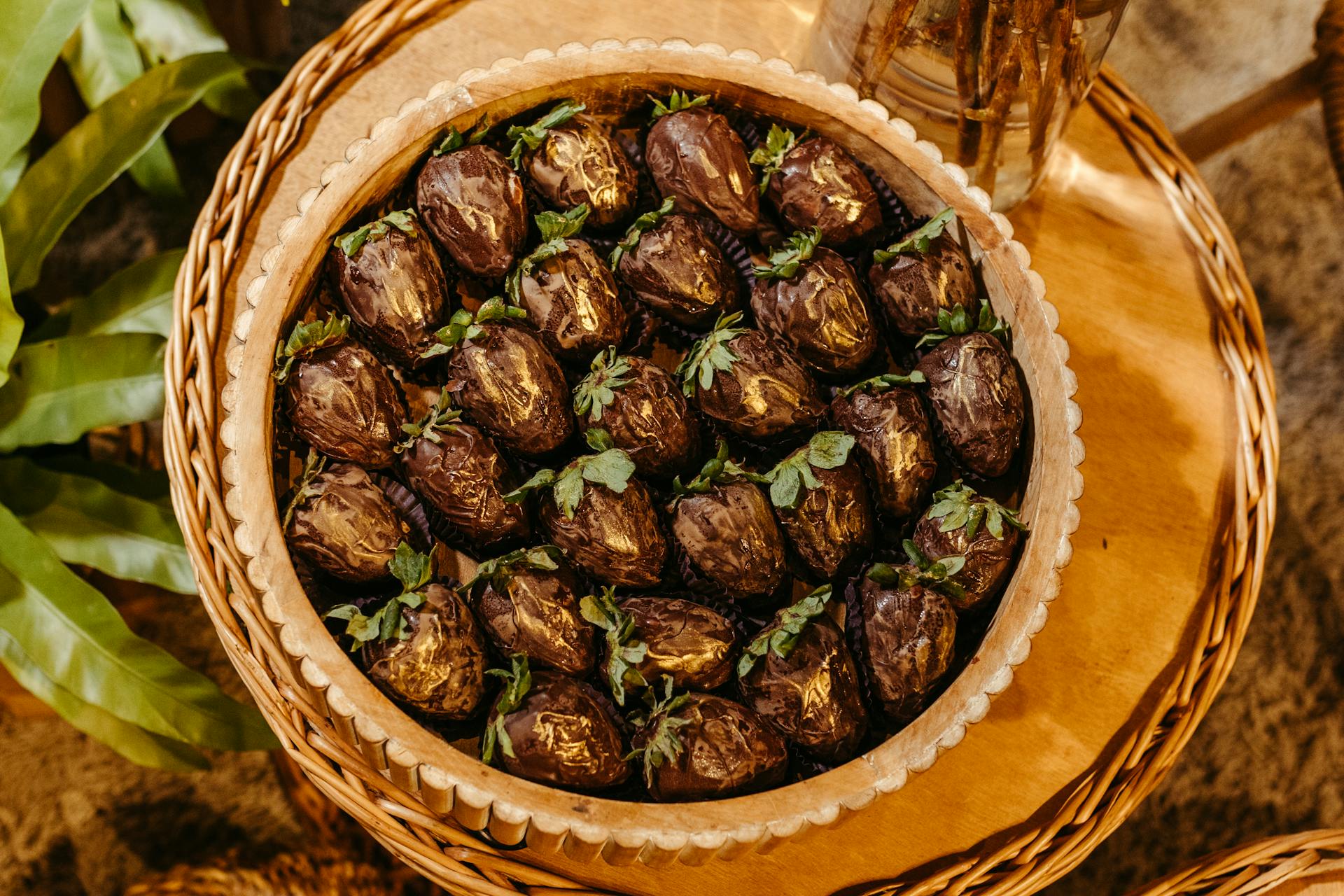 Elegant display of chocolate-covered dates with gold accents in a wicker basket.