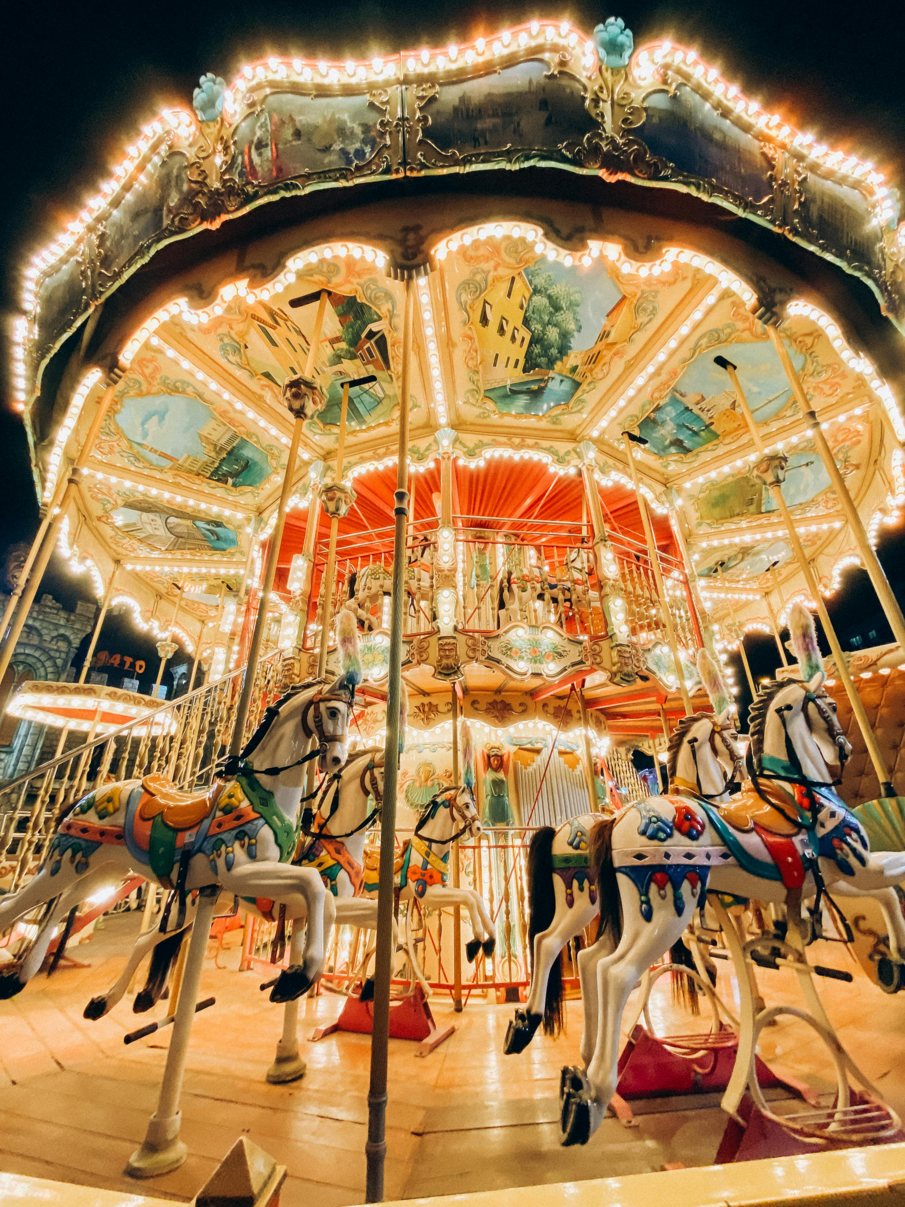 a carousel with horses and carriages at night