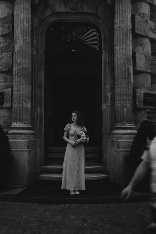 A woman in a wedding dress standing in front of a building