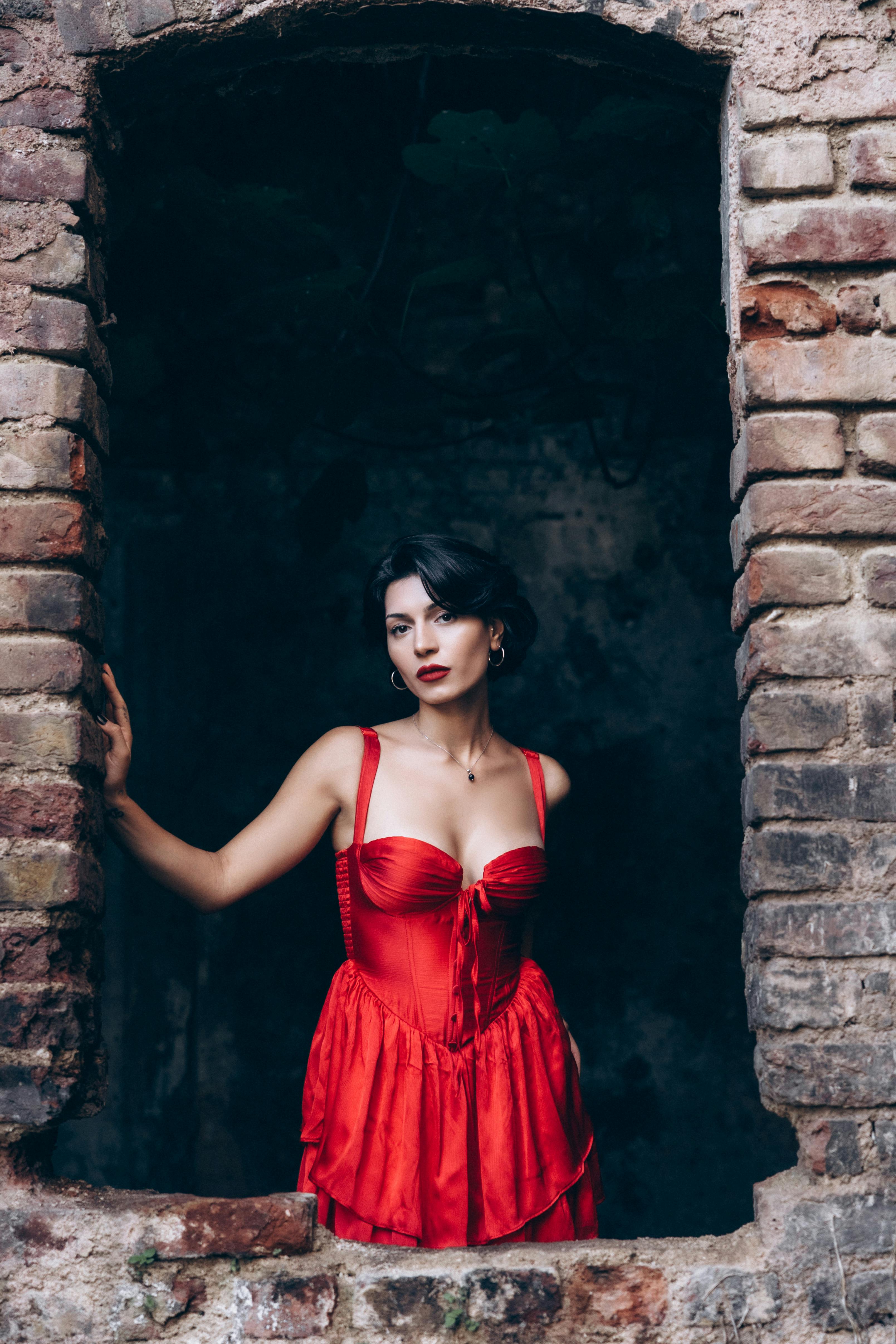 a woman in a red dress looking out of a window